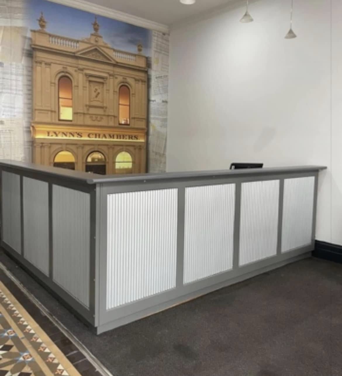 Reception desk inside Lynn's Chambers with a heritage mural of the building behind it